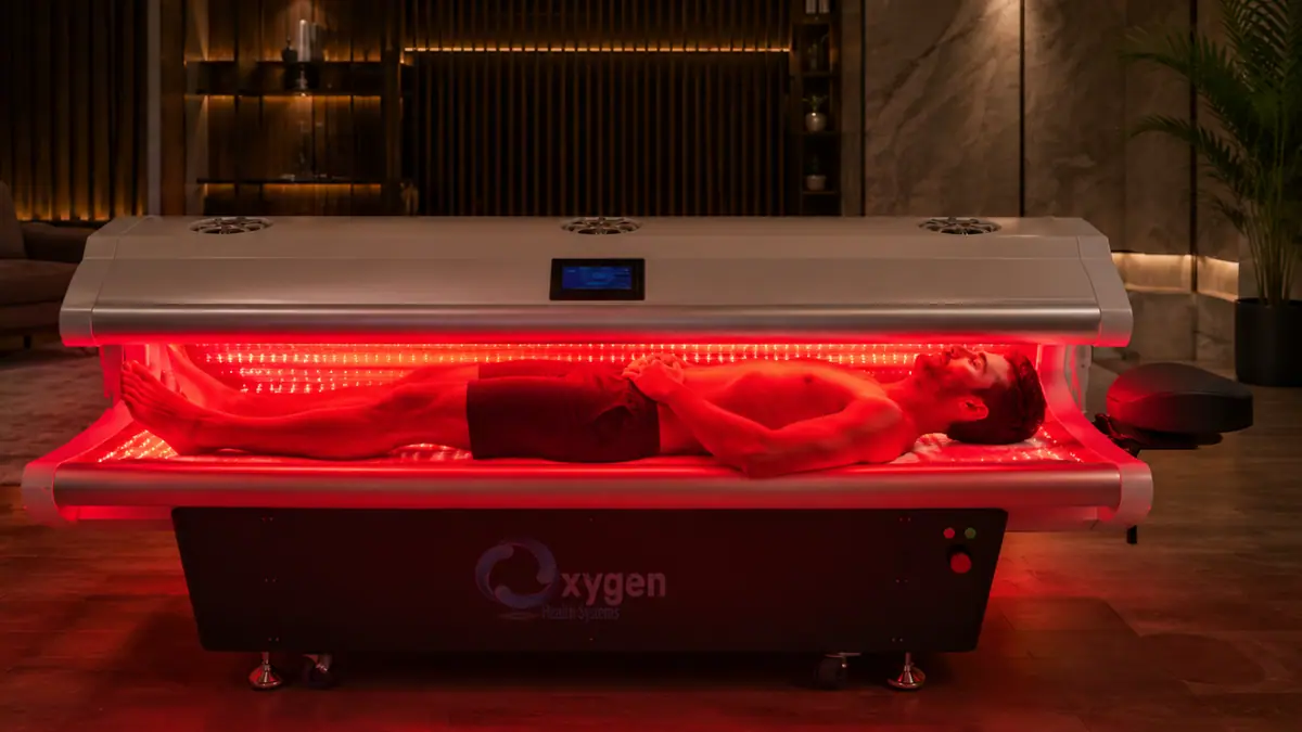 Man lying inside the MitoBooster XL bed with full-body red light illumination