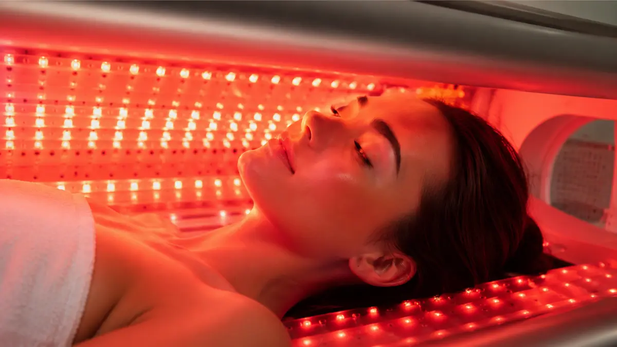 Close-up of a woman's face bathed in red light therapy inside the MitoBooster XL